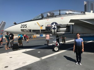Sierra Smith stands in front of an F-14 Tomcat on the USS Midway, one of America's longest serving aircraft carriers.